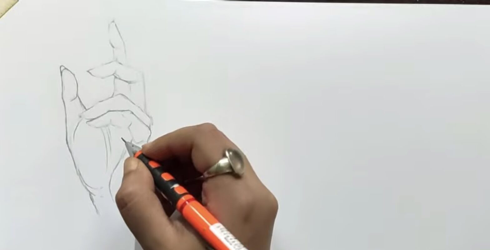 An artist's hand drawing a detailed hand gesture with the index finger pointing upwards, holding a mechanical pencil, with a ring visible on the drawing hand